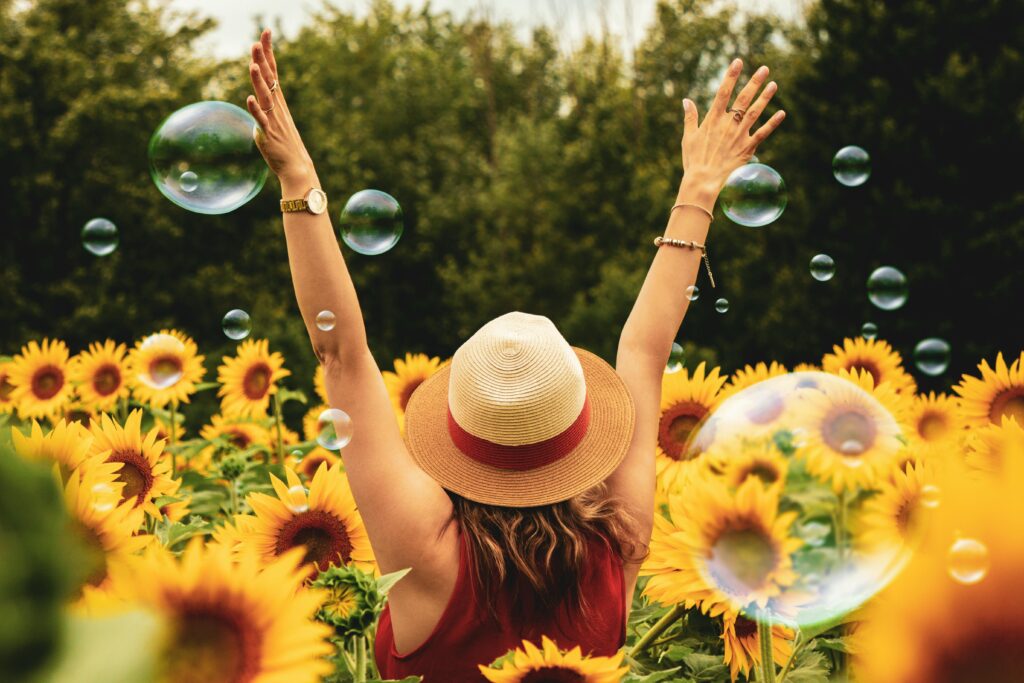 pexels-photo-1263986-1263986 A joyful woman in a sunflower field with bubbles, expressing happiness on a summer day.
